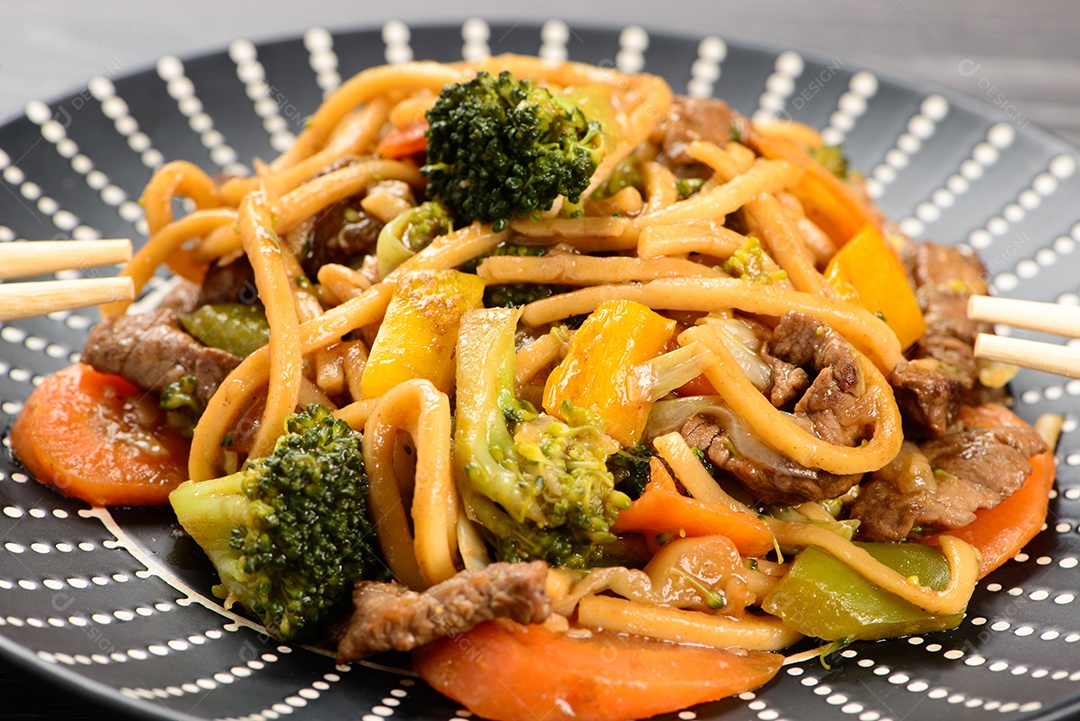 Yakisoba em um prato preto sobre uma mesa