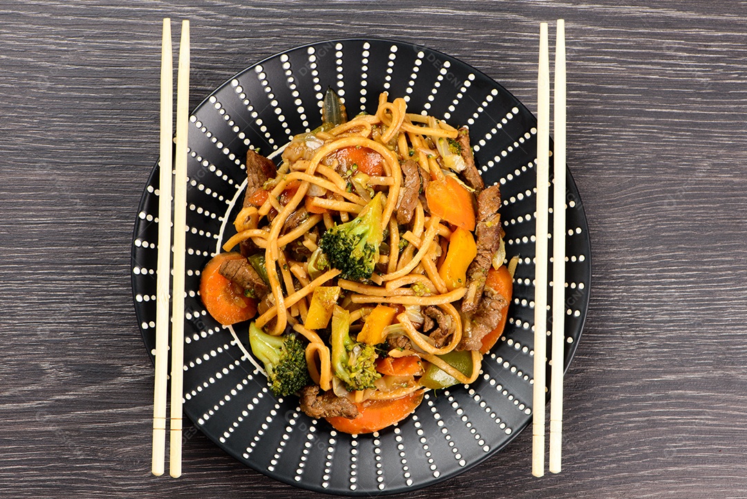 Yakisoba em um prato preto sobre uma mesa
