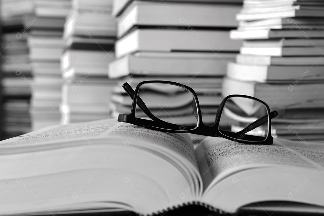 Livros sobre a mesa e estantes ao fundo