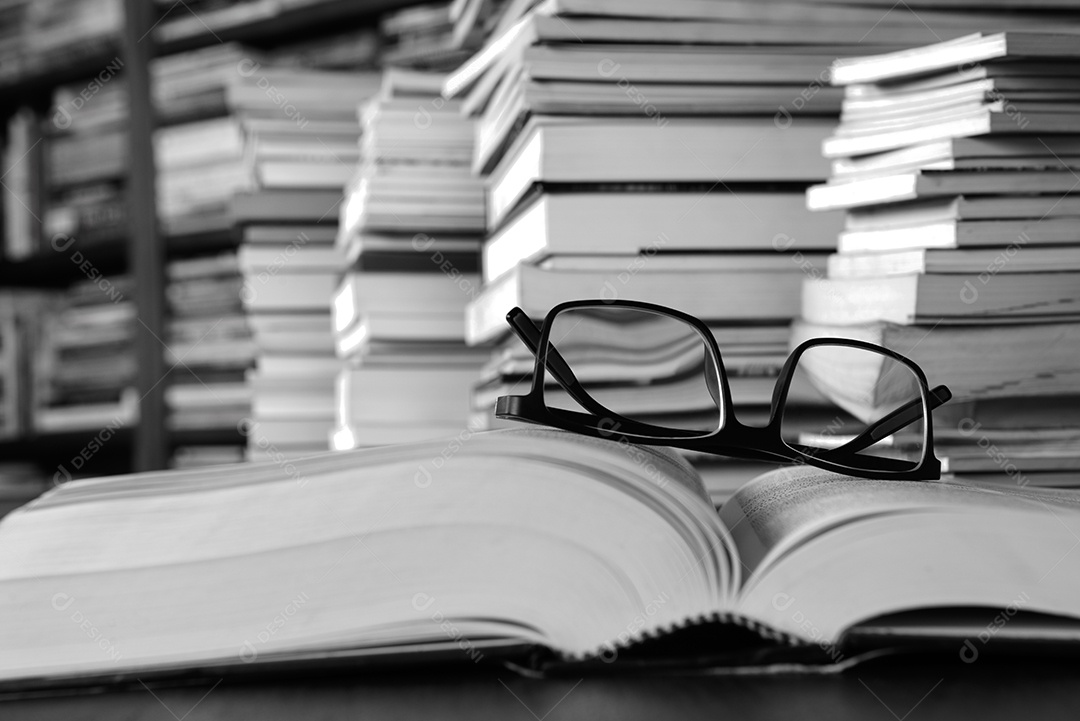 Livros sobre a mesa e estantes ao fundo