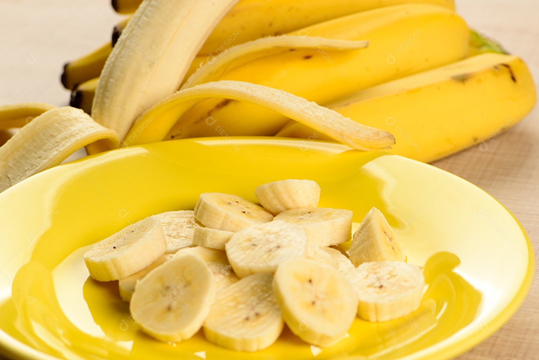 Banana inteira e fatiada em prato amarelo