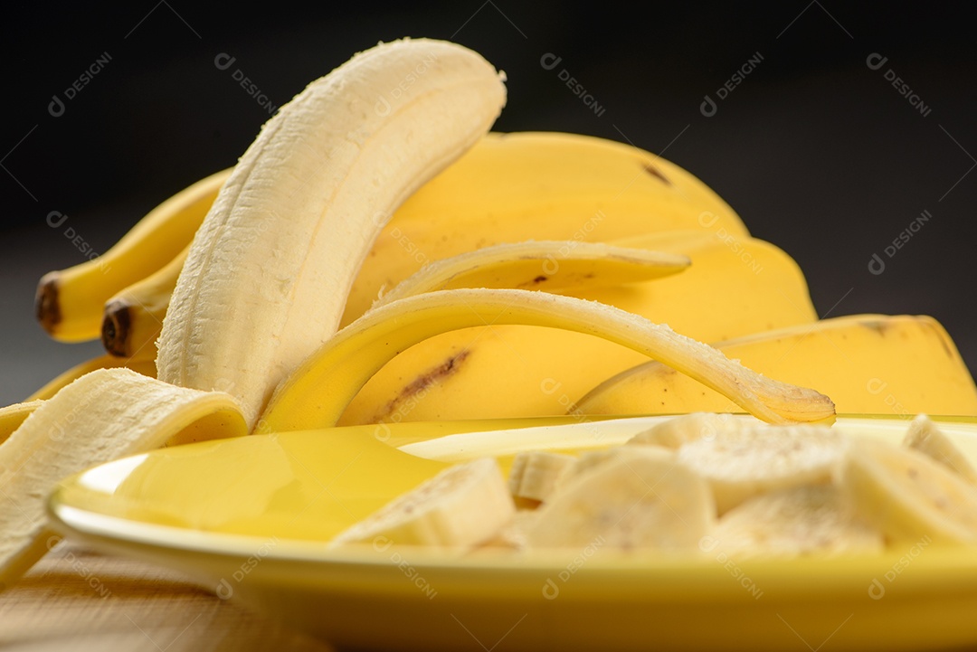 Banana inteira e fatiada em prato amarelo