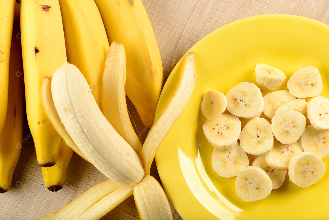 Banana inteira e fatiada em prato amarelo