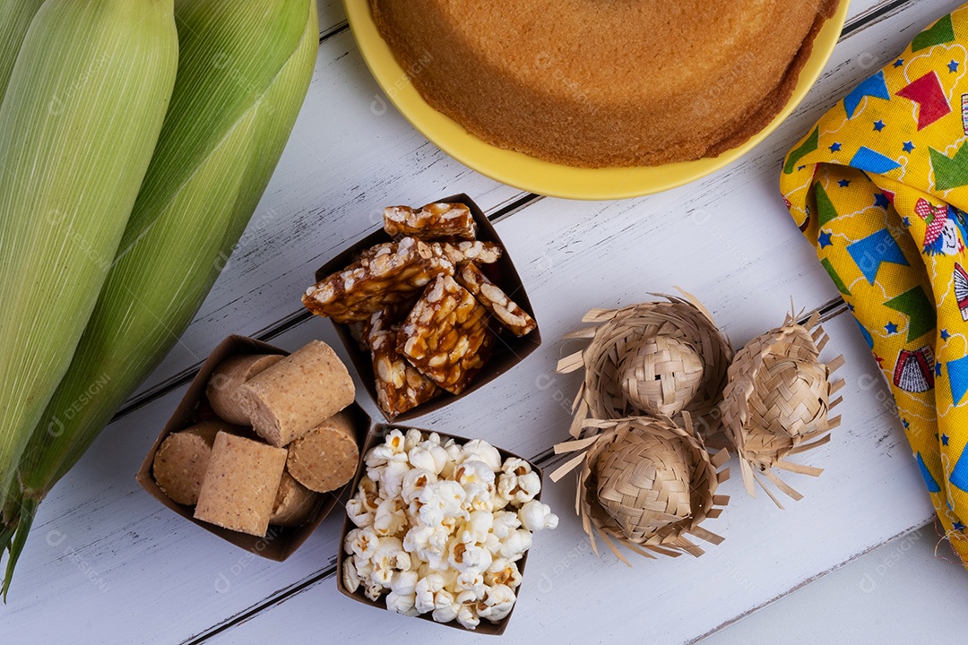 Milho verde e doces da festa junina na mesa de madeira branca.