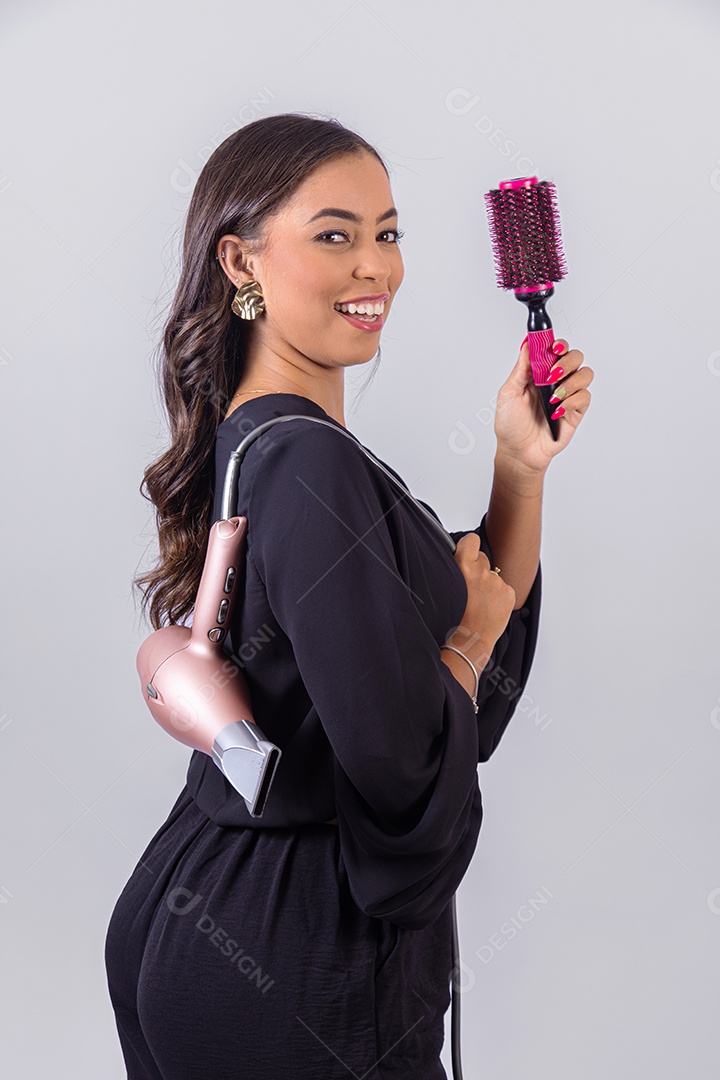 Linda mulher bonita jovem segurando escova e secador sobre fundo isolado