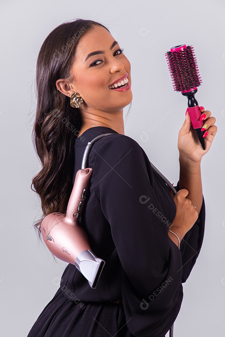 Linda mulher bonita jovem segurando escova e secador sobre fundo isolado