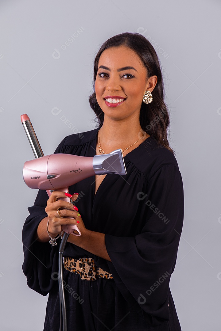 Linda mulher bonita jovem segurando escova e secador sobre fundo isolado