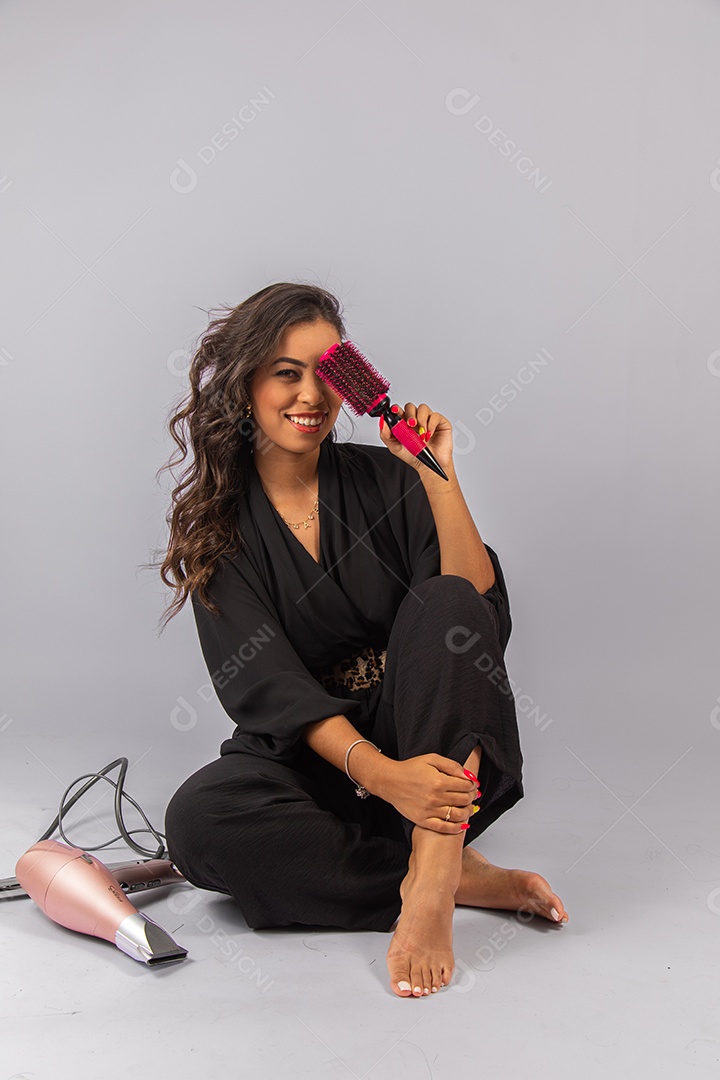 Linda mulher bonita jovem segurando escova e secador sobre fundo isolado