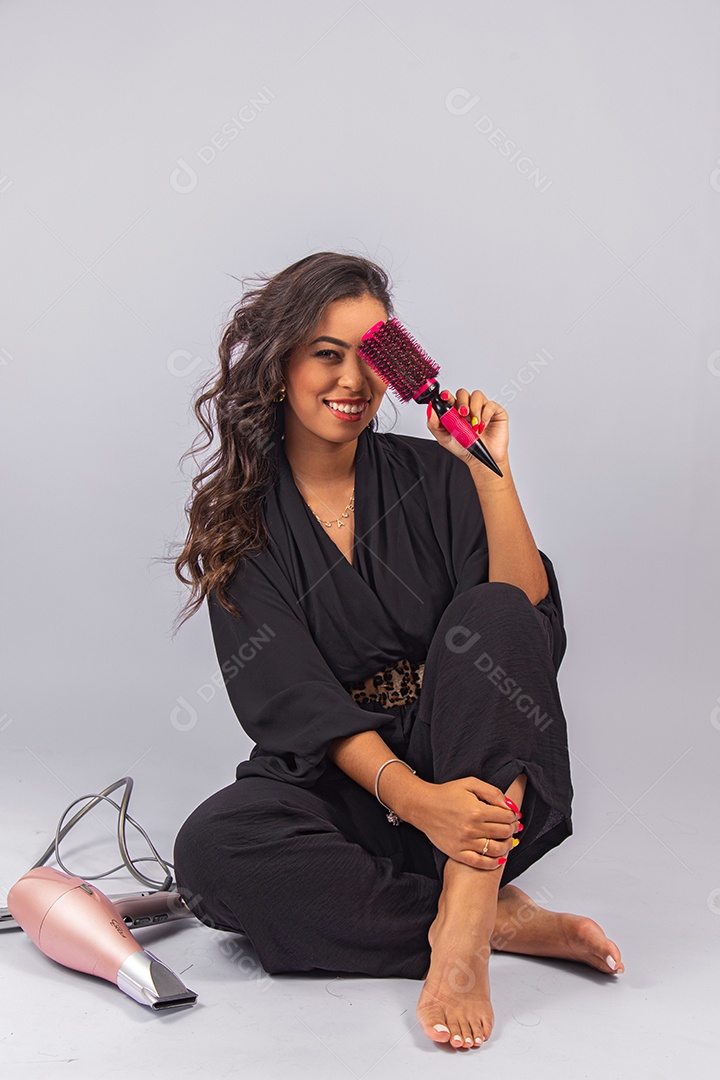 Linda mulher bonita jovem segurando escova e secador sobre fundo isolado