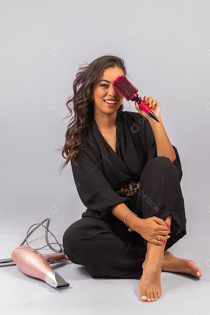 Linda mulher bonita jovem segurando escova e secador sobre fundo isolado