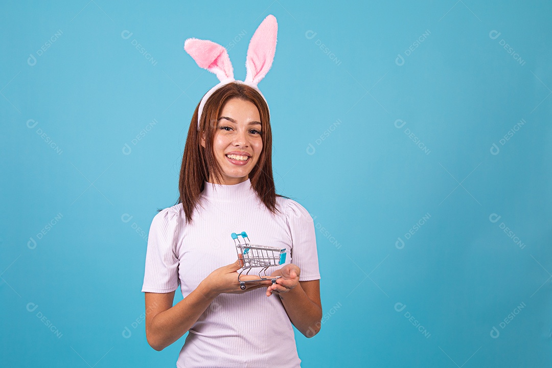 Mulher fantasiada de coelho páscoa segurando carrinho de supermercado