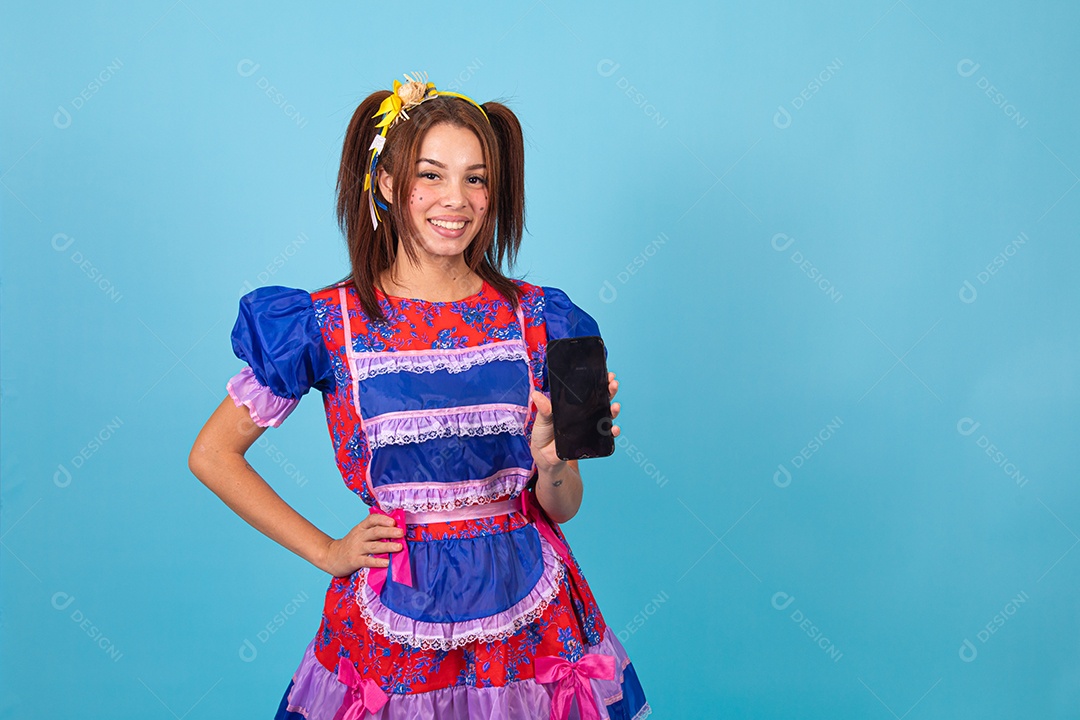 Mulher jovem fantasiada celebrando festas juninas segurando celular smartphone