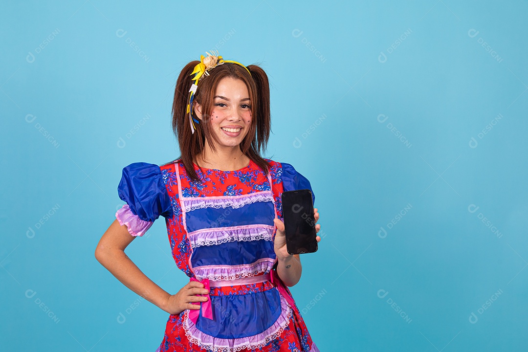 Mulher jovem fantasiada celebrando festas juninas segurando celular smartphone