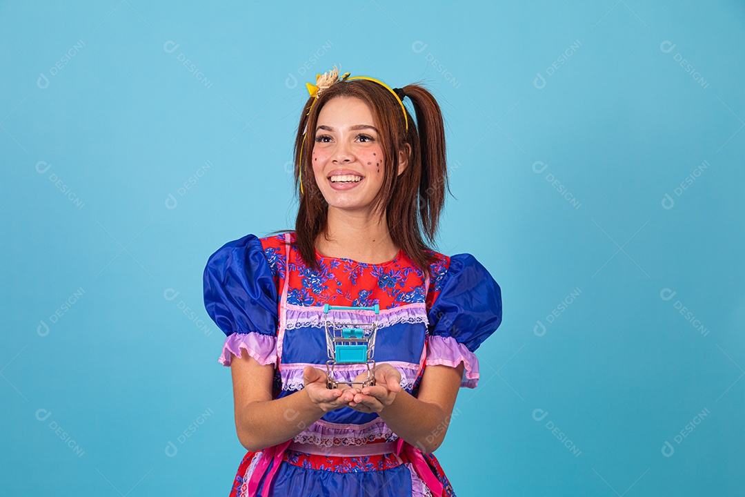 Mulher jovem fantasiada celebrando festas juninas segurando carrinho de compras de supermercado