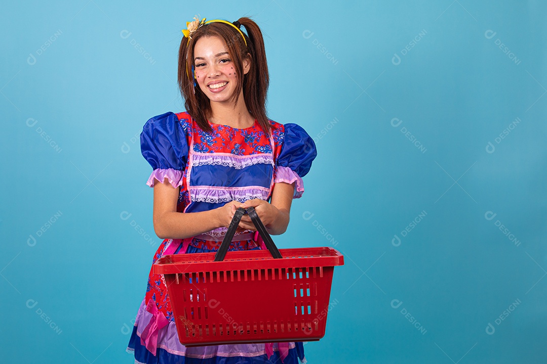 Mulher jovem fantasiada celebrando festas juninas segurando cesta de supermercado
