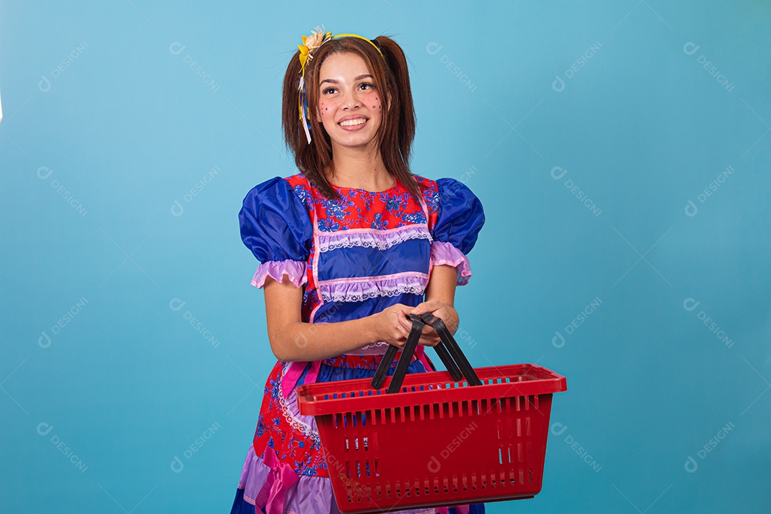 Mulher jovem fantasiada celebrando festas juninas segurando cesta de supermercado