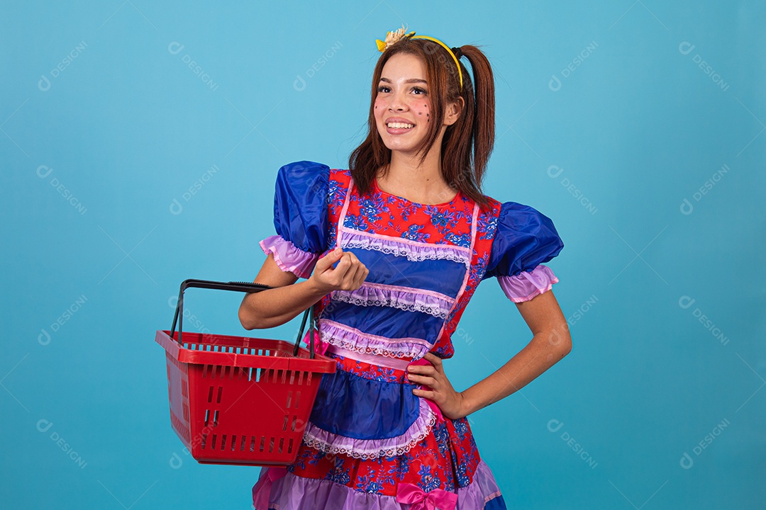Mulher jovem fantasiada celebrando festas juninas segurando cesta de supermercado