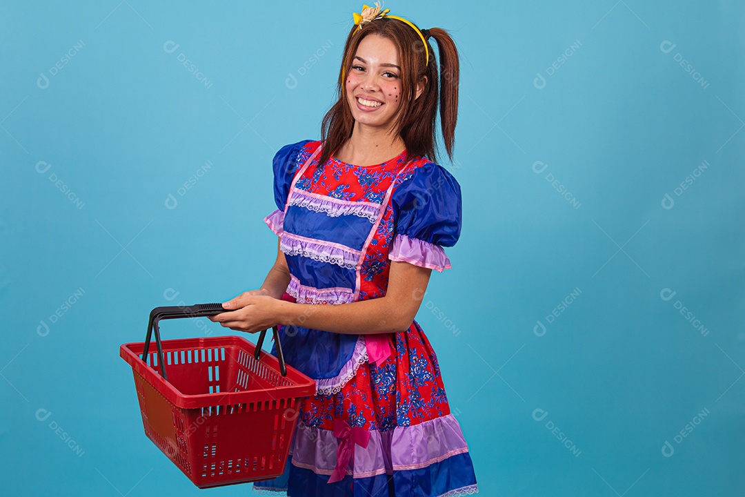 Mulher jovem fantasiada celebrando festas juninas segurando cesta de supermercado