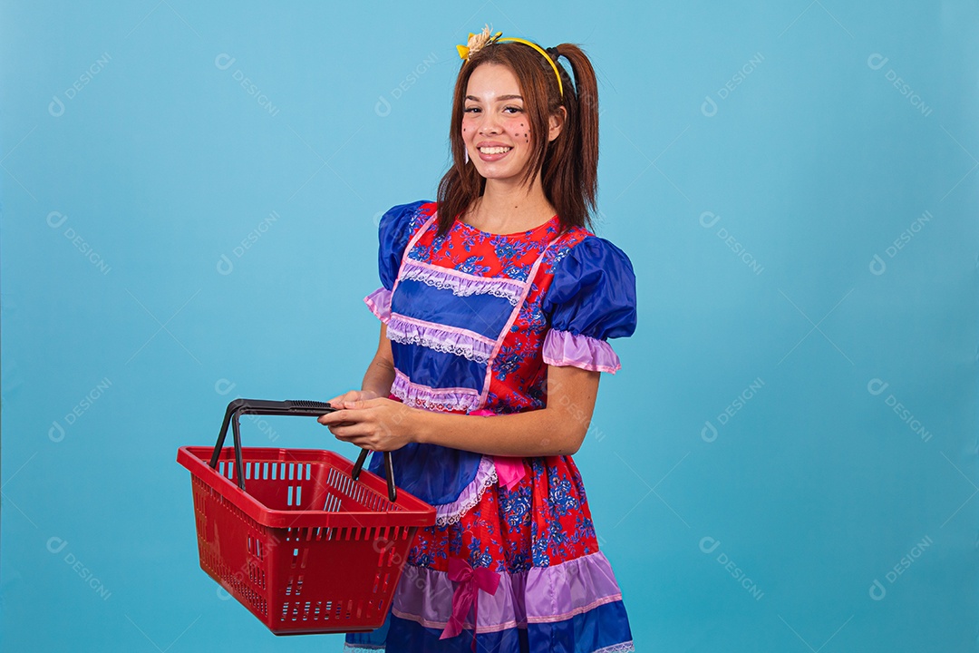 Mulher jovem fantasiada celebrando festas juninas segurando cesta de supermercado