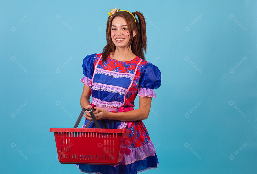 Mulher jovem fantasiada celebrando festas juninas segurando cesta de supermercado