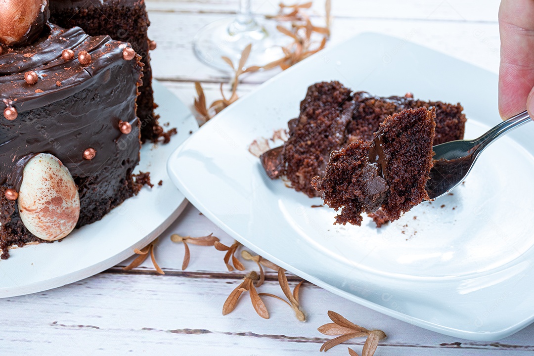 Masculino mão segurando um pedaço de bolo de chocolate com um garfo.