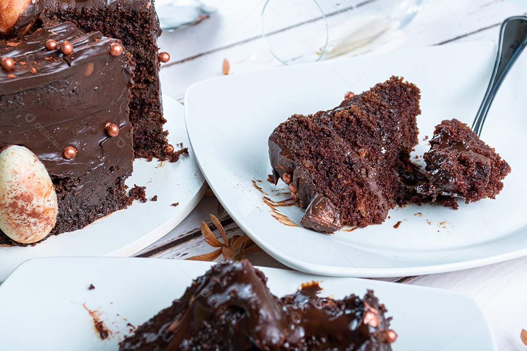 Fatia de bolo de chocolate com recheio de ganache escuro ao lado de um garfo