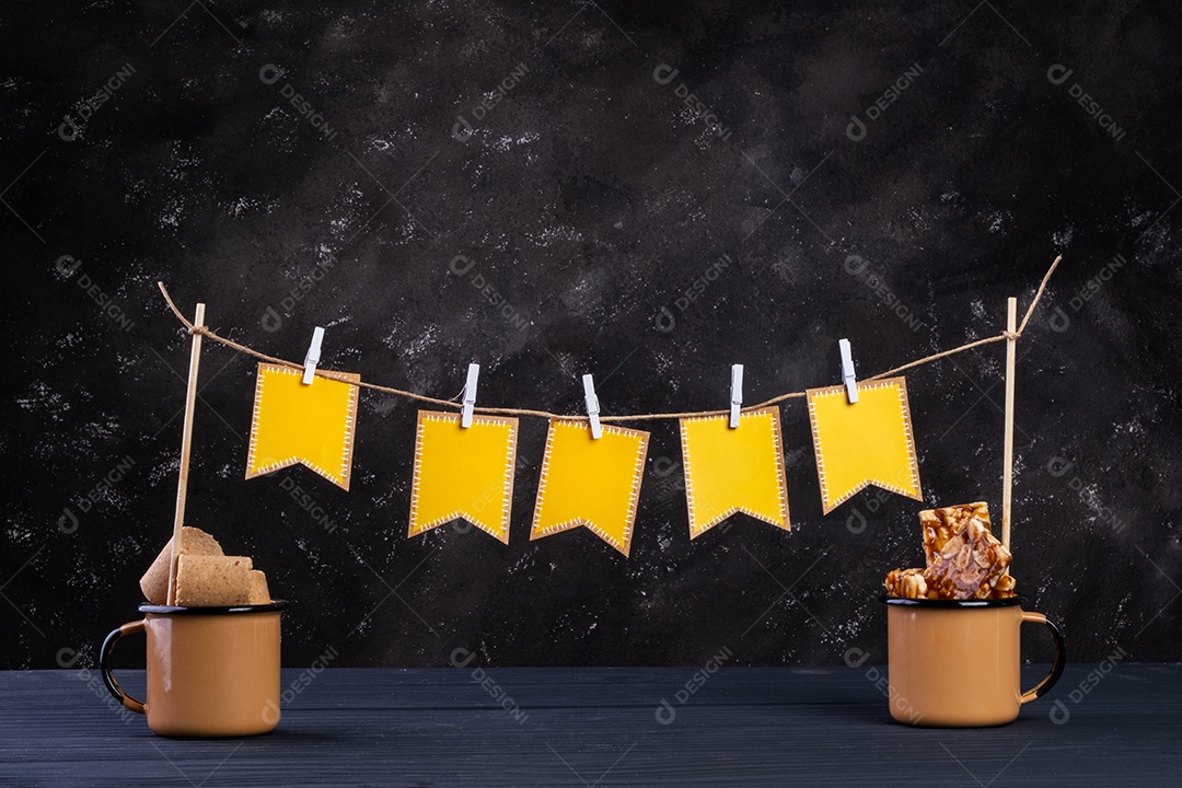 Varal feito de bandeiras de papel e barbante com canecas de doces