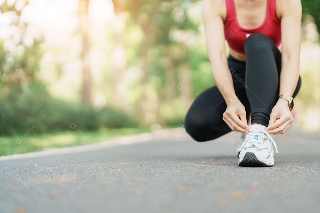 Mulher jovem atleta amarrando tênis no parque ao ar livre