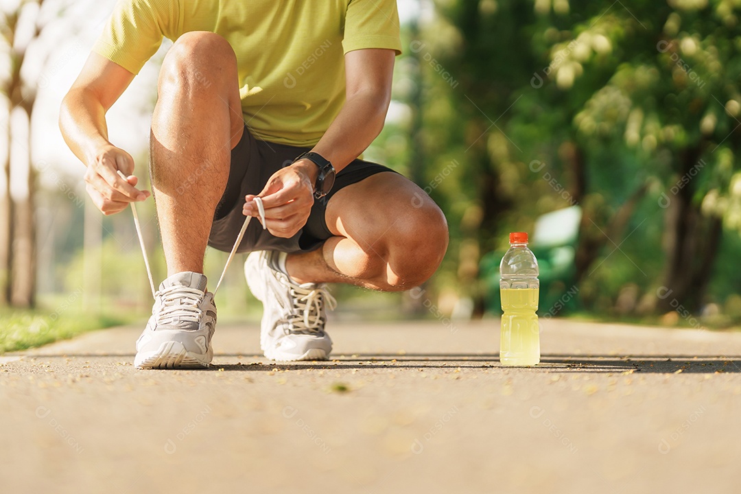 Homem jovem atleta amarrando tênis de corrida com água Energy Drink