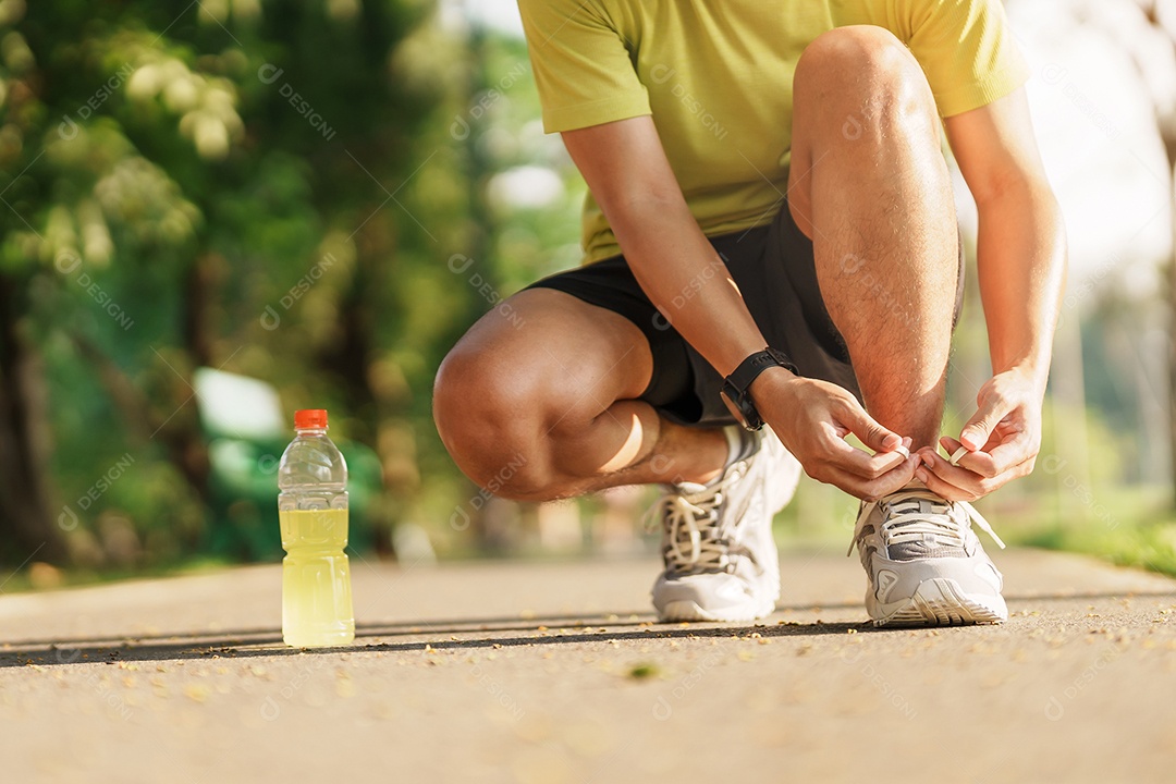 Homem jovem atleta amarrando tênis de corrida com água Energy Drink