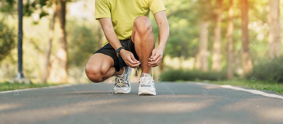 Homem jovem atleta amarrando tênis no parque ao ar livre