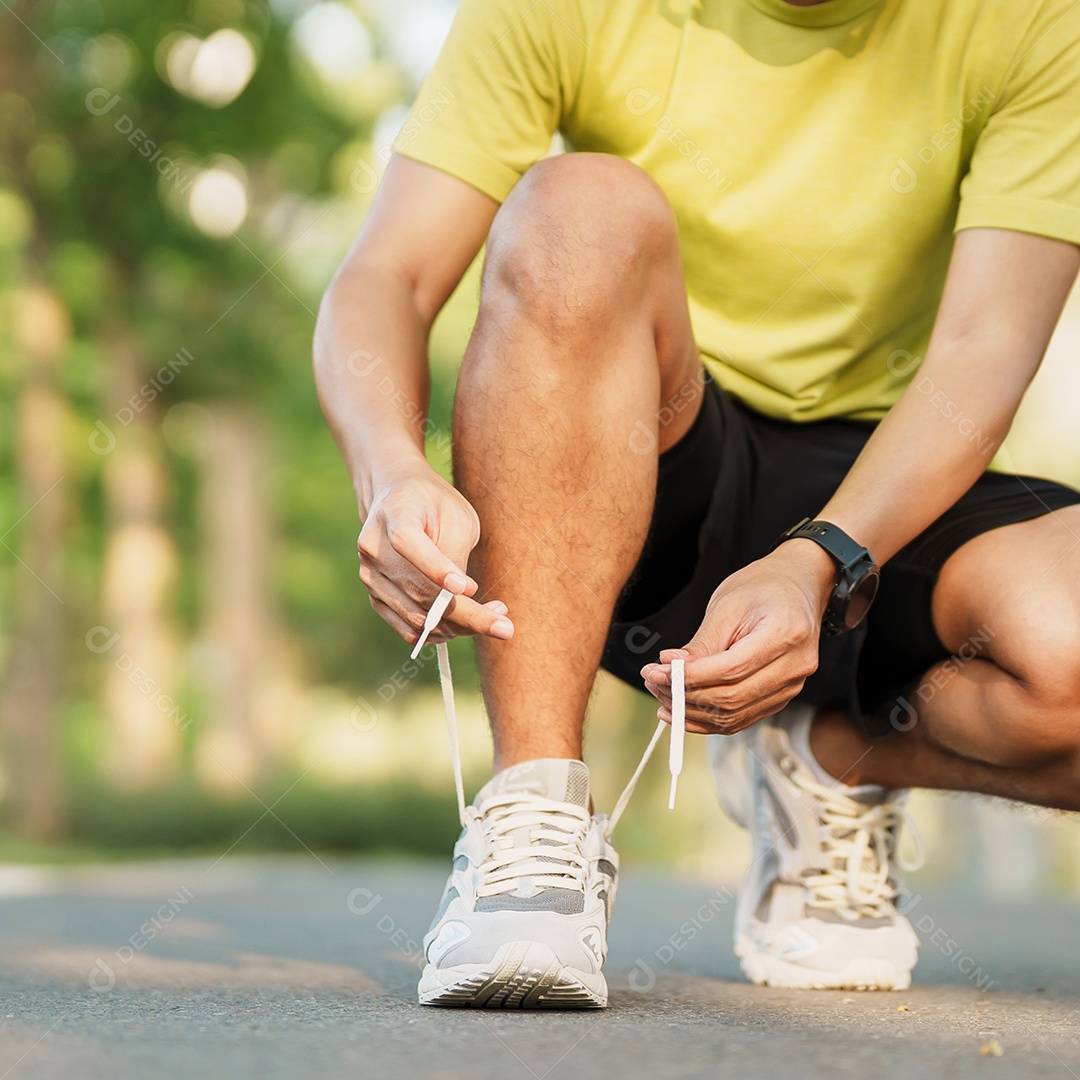 Homem jovem atleta amarrando tênis no parque ao ar livre