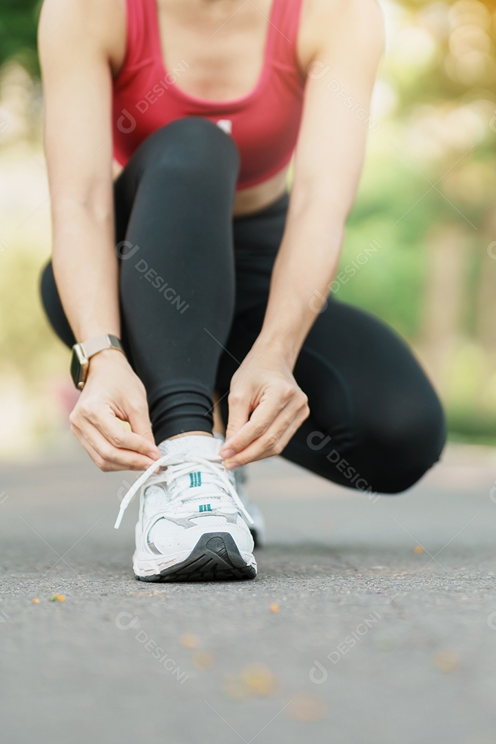 Mulher jovem atleta amarrando tênis no parque ao ar livre