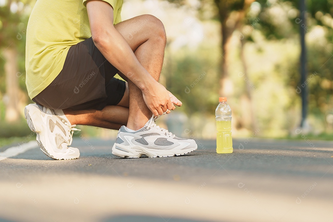 Homem jovem atleta amarrando tênis de corrida com água Energy Drink