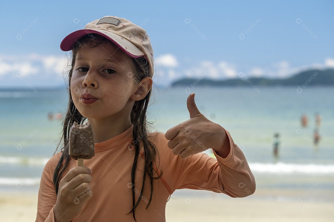 Menina comendo sorvete com praia ao fundo