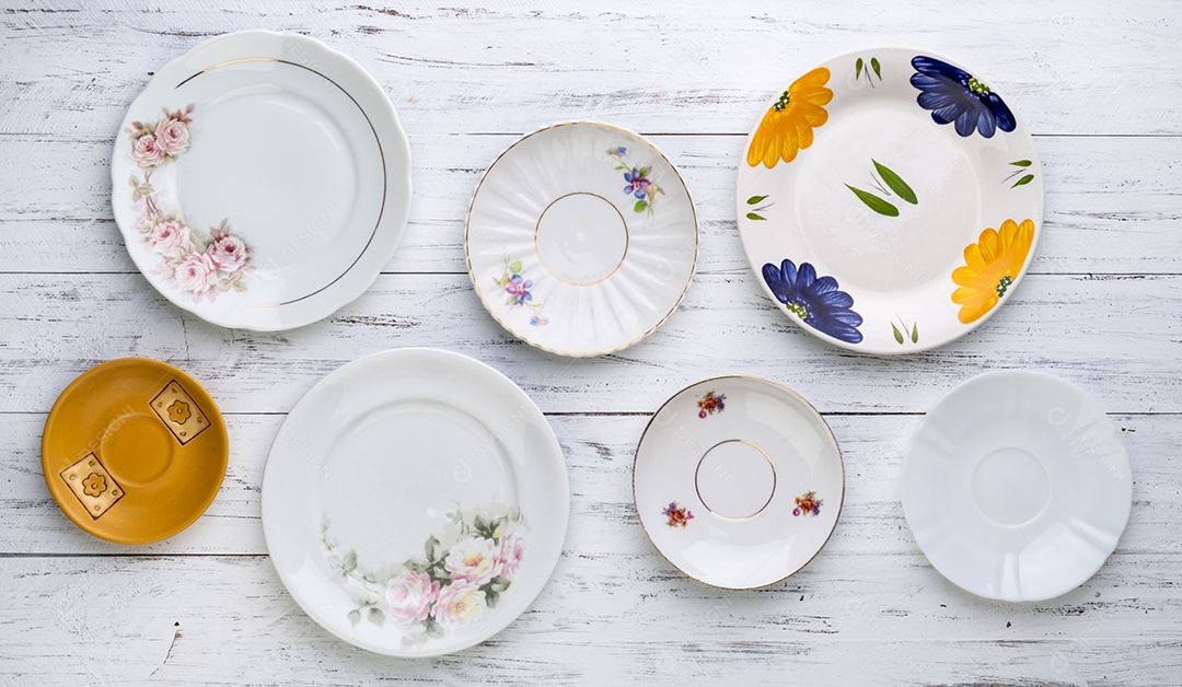 Diversos pratos antigos de cerâmica vintage sobre a mesa de madeira branca