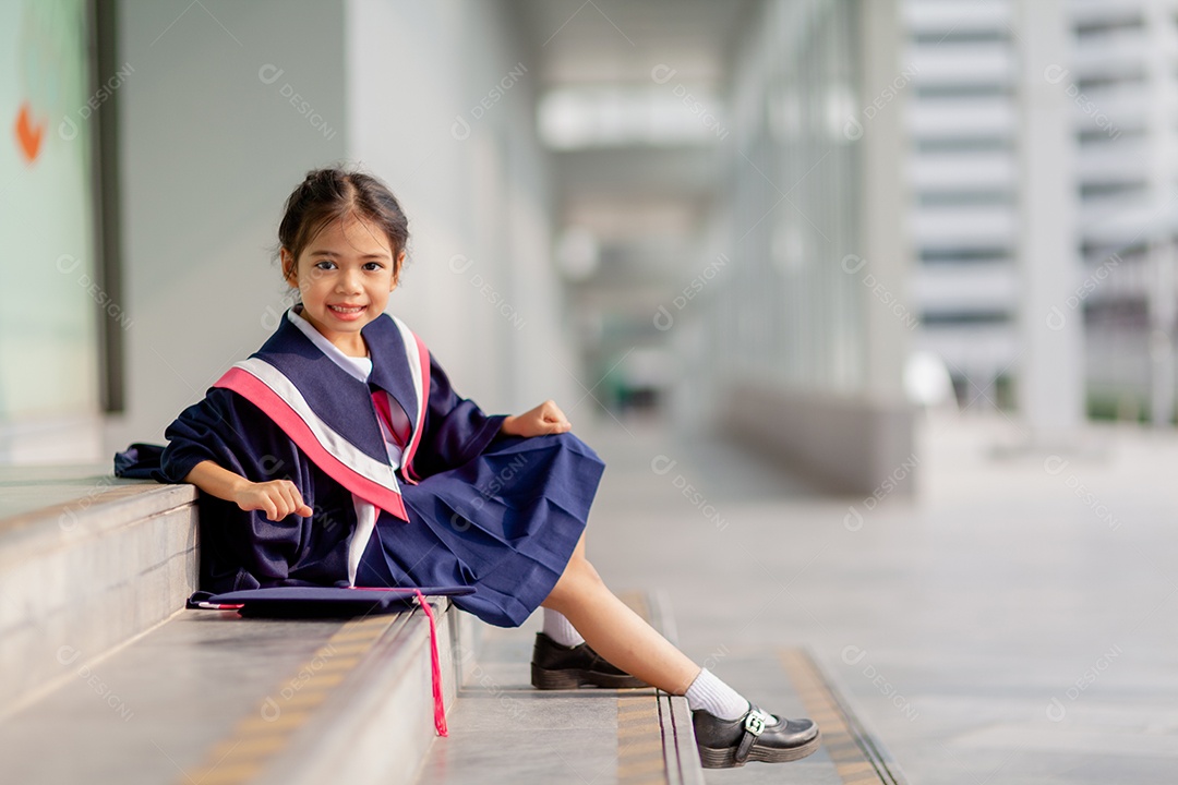 Meninas asiáticas felizes em vestidos de formatura no dia da formatura na escola.