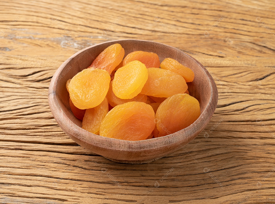 Damascos secos em uma tigela sobre a mesa de madeira