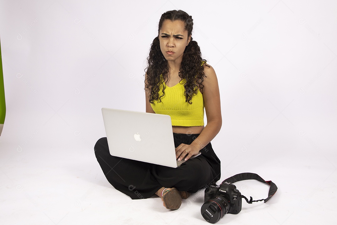 Linda mulher garota jovem segurando notebook e uma câmera fotográfica sobre fundo isolado