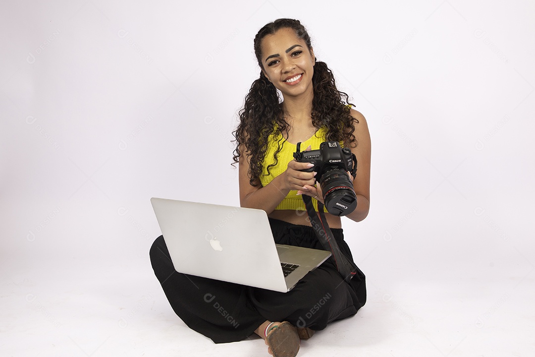 Linda mulher garota jovem segurando notebook e uma câmera fotográfica sobre fundo isolado
