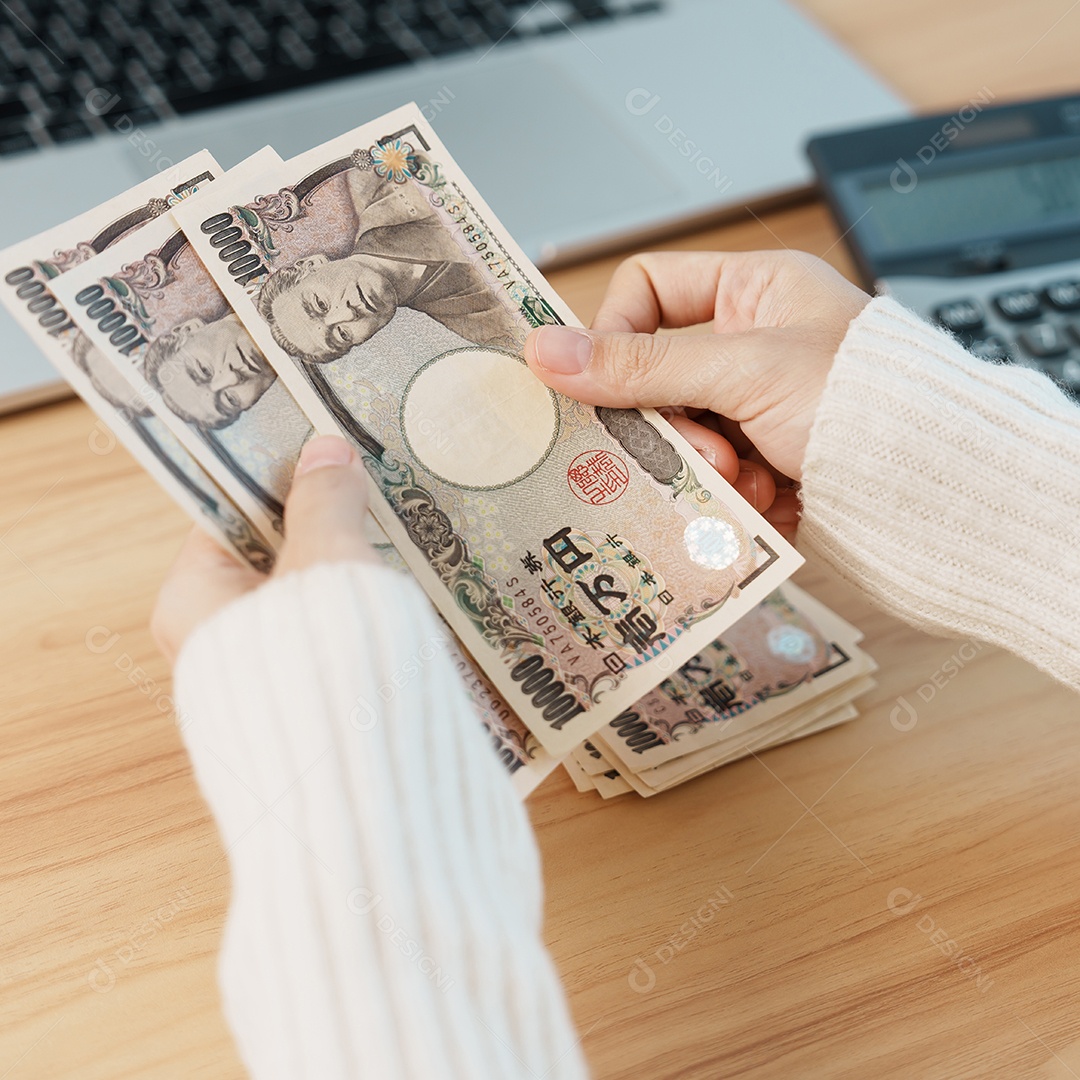 Mão de mulher contando notas de ienes japoneses com calculadora.