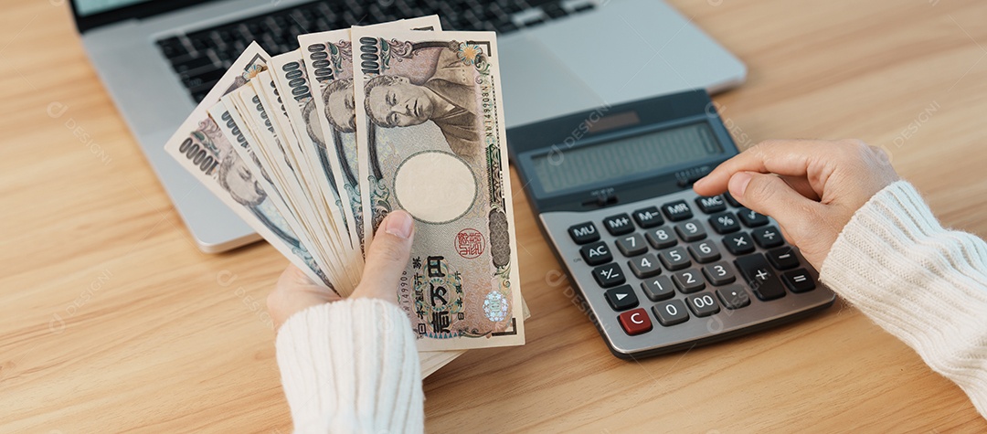 Mão de mulher contando notas de ienes japoneses com calculadora.