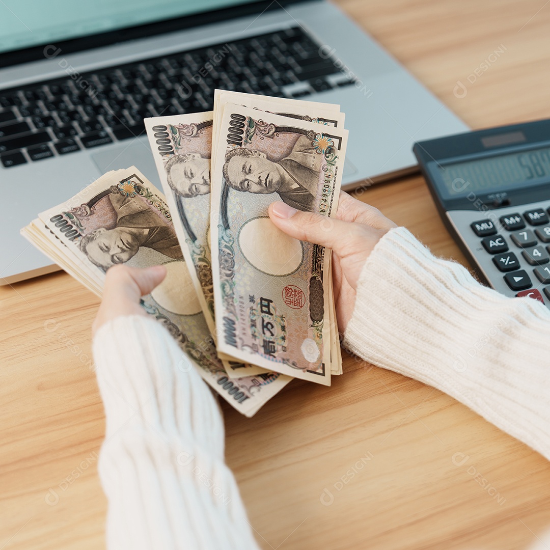 Mão de mulher contando notas de ienes japoneses com calculadora.