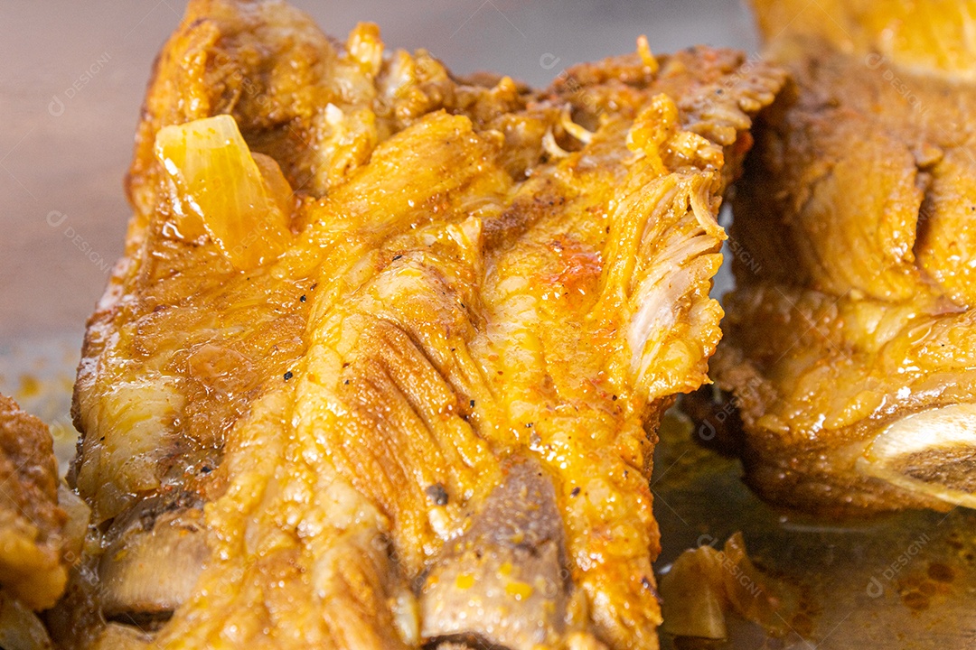 Costelinha suína cozida na panela de pressão sobre mesa de madeira.