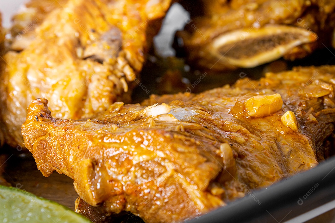 Costelinha suína cozida na panela de pressão sobre mesa de madeira.
