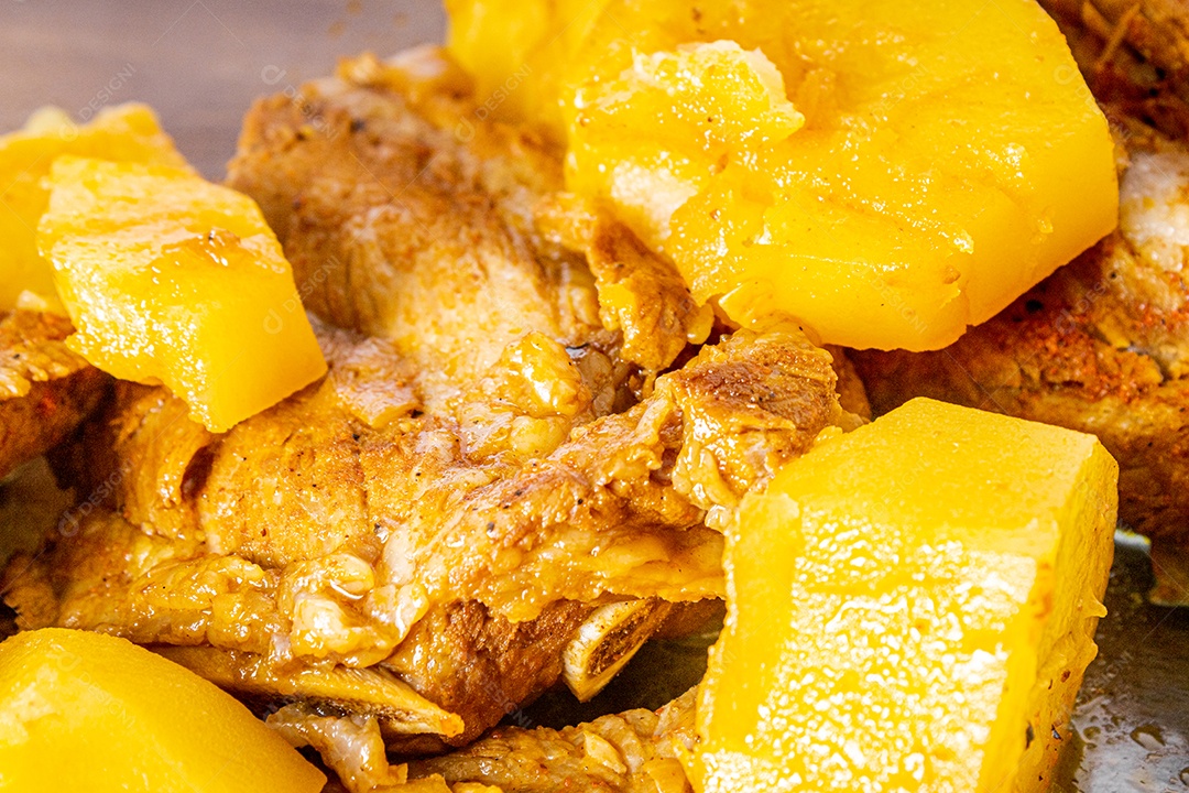 Costelinha suína cozida na panela de pressão sobre mesa de madeira.