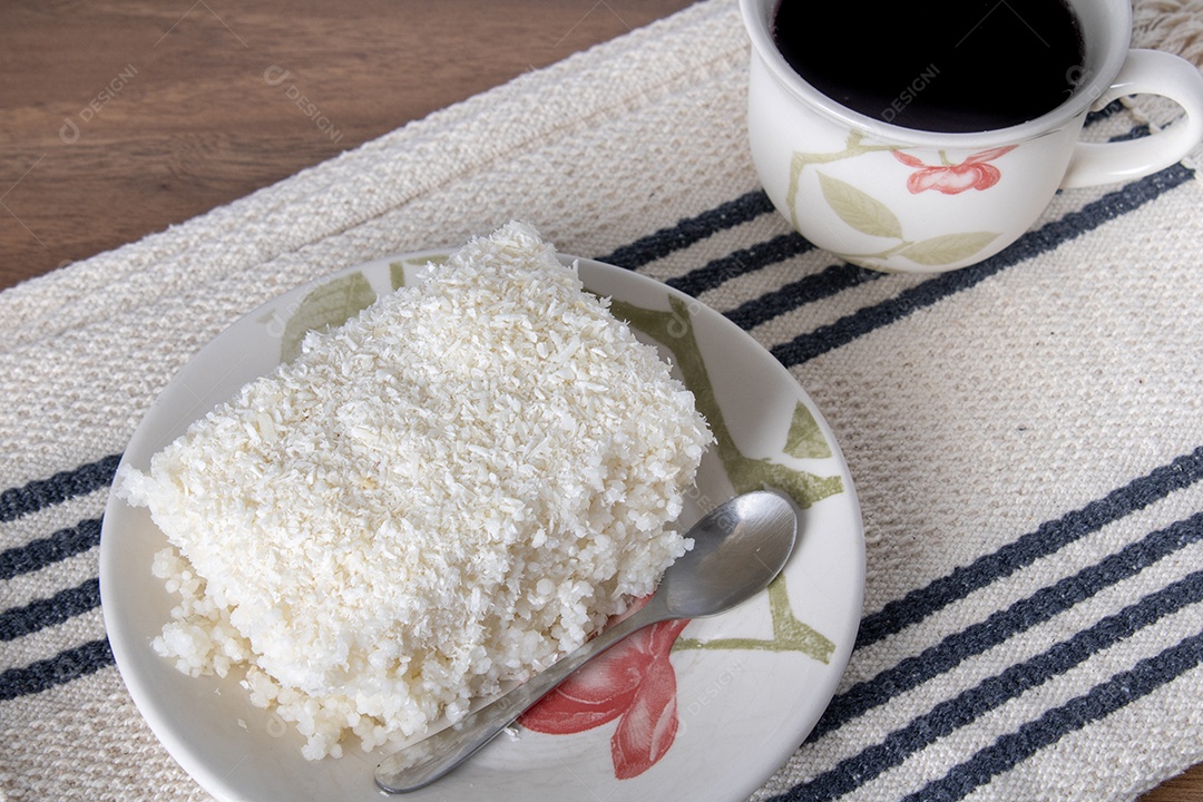 Pedaço de cuscuz em pires de porcelana sobre mesa de madeira