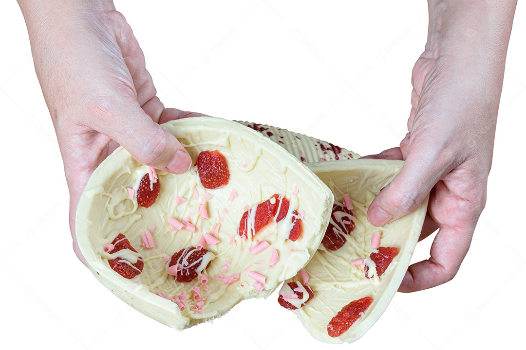 Confeiteiro segurando metade de um ovo de Páscoa de chocolate branco com morangos cristalizados.
