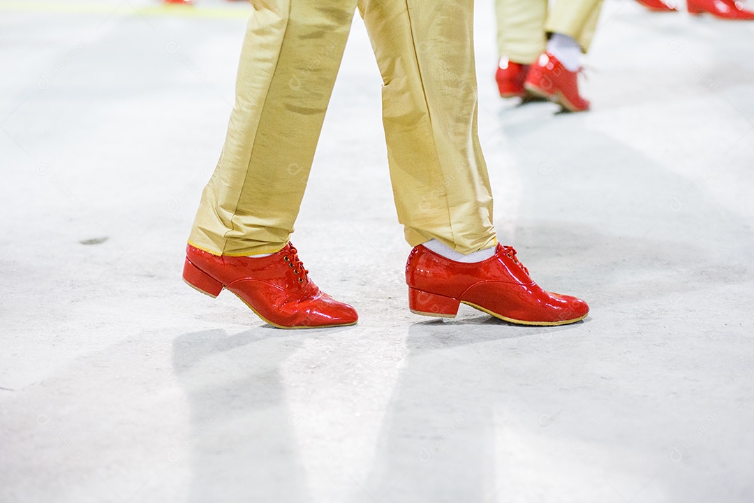 Sambista com calças cor de areia e sapatos vermelhos se apresentando no Rio de Janeiro, Brasil.