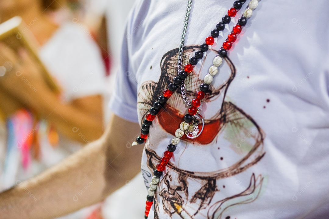 camisa branca com desenho de malandro e guias de umbanda vermelhas e brancas durante o carnaval do Rio de Janeiro, Brasil.